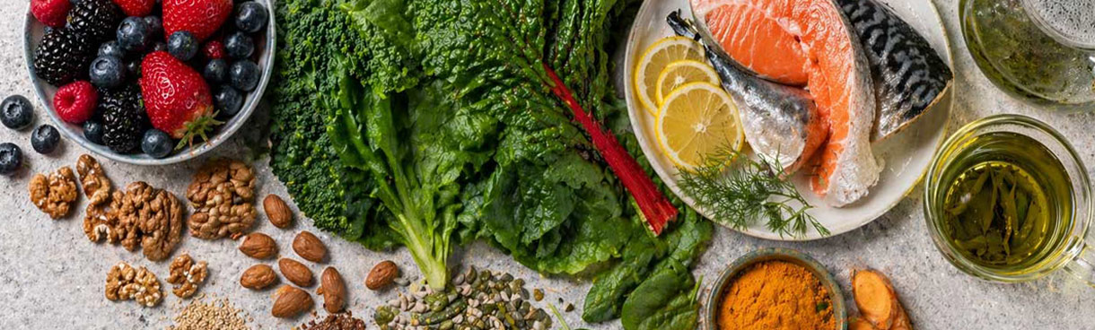 Flatlay mit Beeren, Blattgemüse, Nüssen, Fisch und grünem Tee — Lebensmittel für Haut- und Zellgesundheit